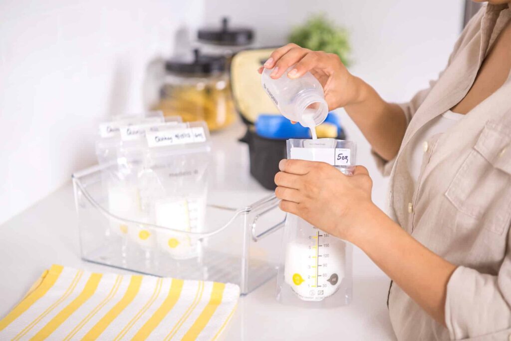 Medela breast pump bottle being emptied into a bag